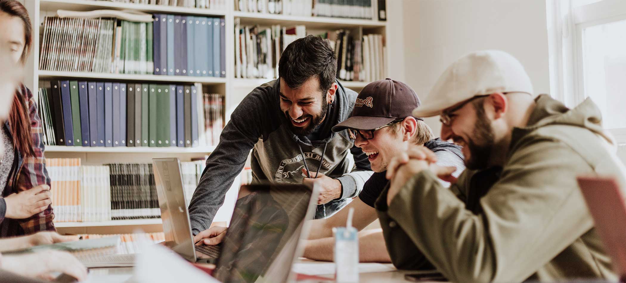 people laughing while looking at a computer