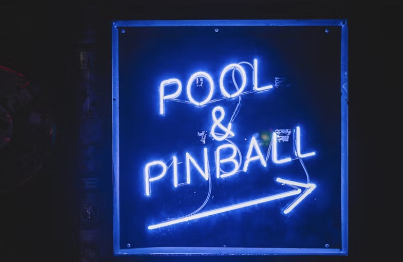 a pool and pinball directional signage that is neon